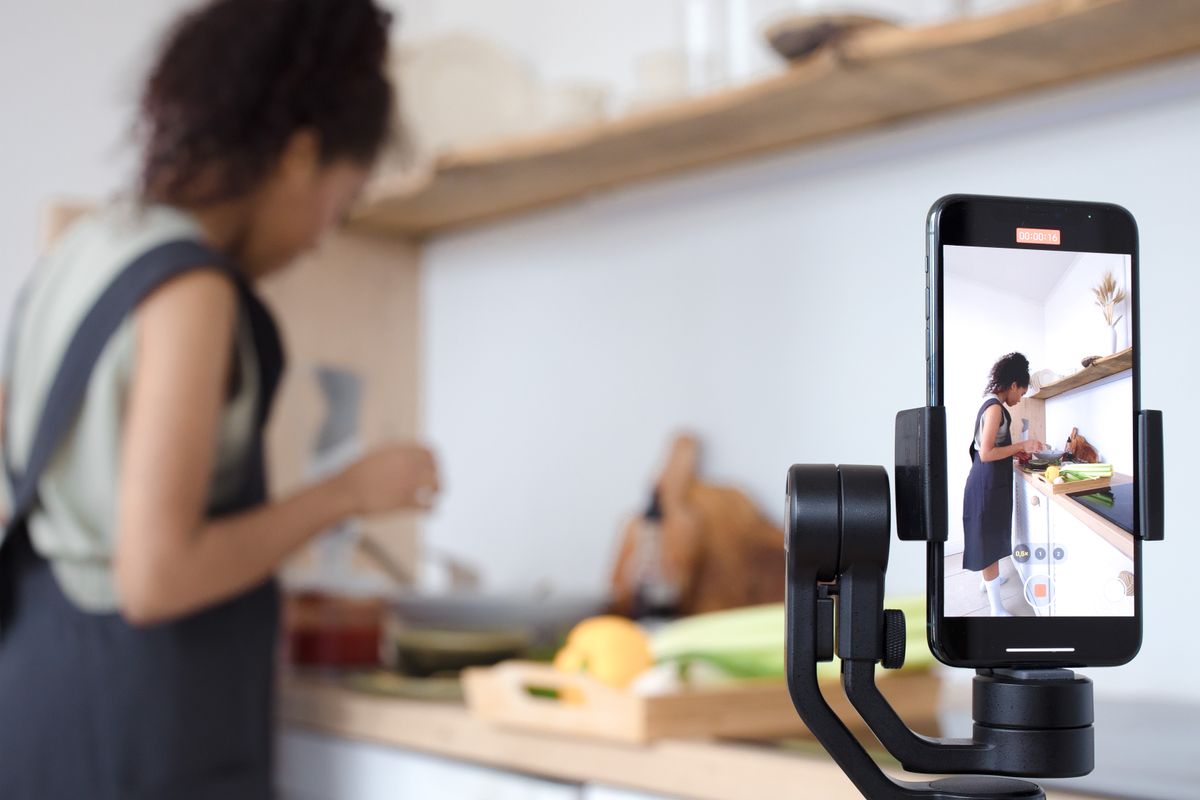 A phone on a gimbal filming a cook at work in the kitchen