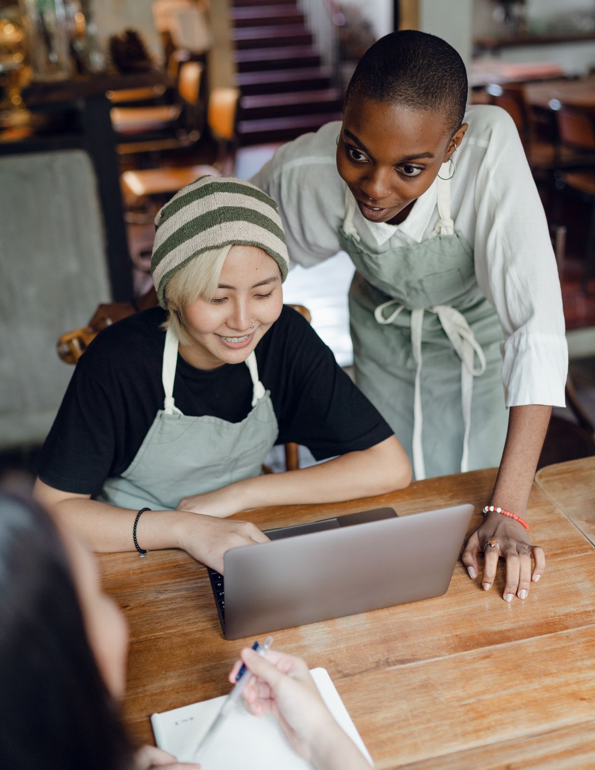 Two café staff reviewing the week's plan together on a laptop