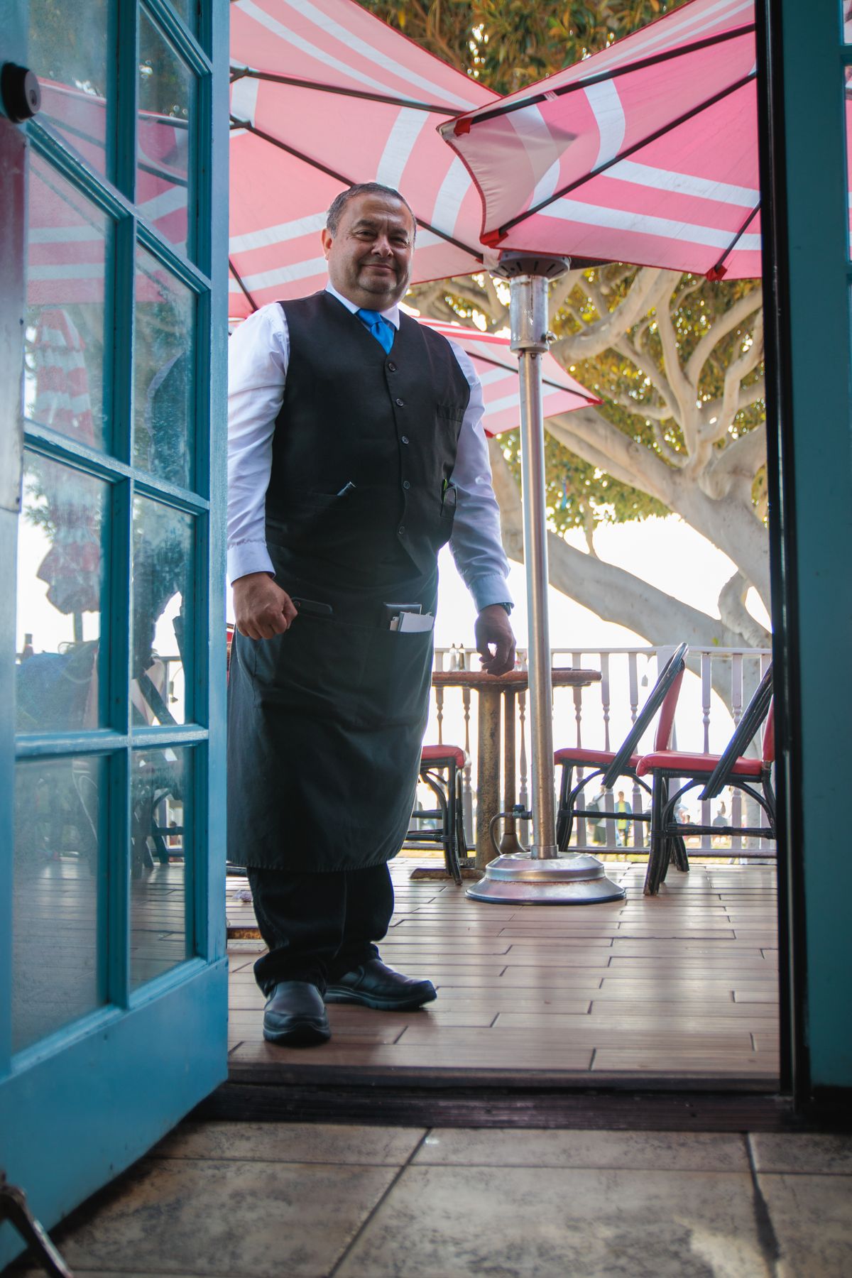 A smiling waiter welcoming guests at the restaurant entrance