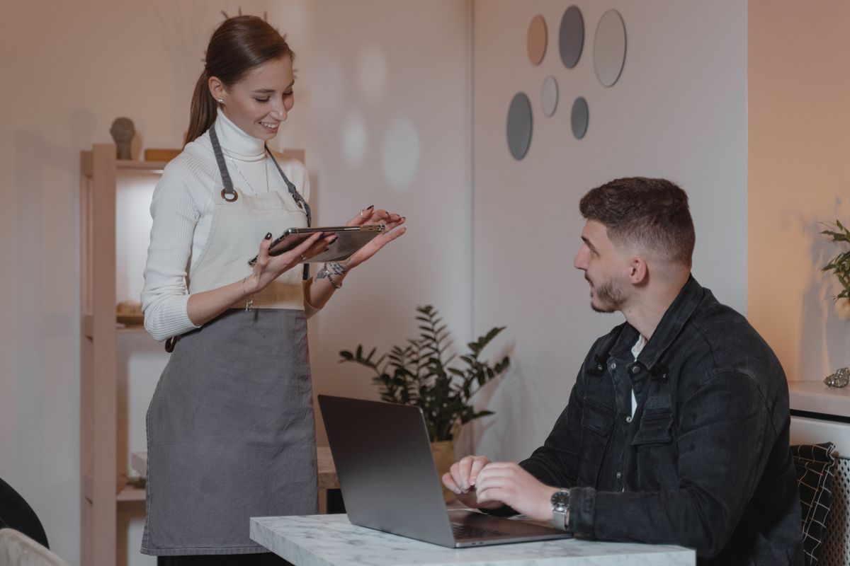 A server showing menu options to a guest on a tablet